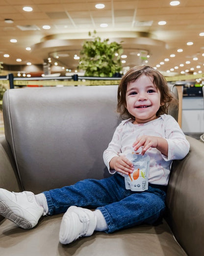 Toddler eating carrot sweet potato pea baby food pouch