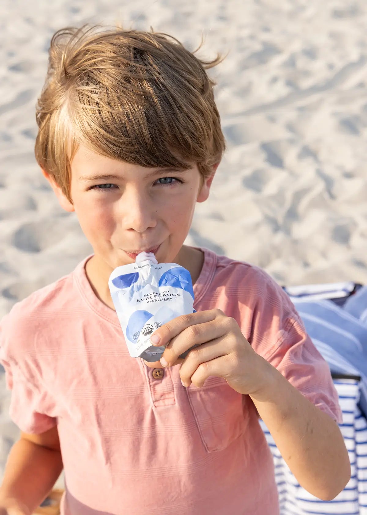 Boy sipping blueberry applesauce pouch from white leaf provisions clean baby food packs
