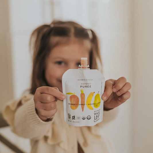 Girl holding White Leaf Provisions organic biodynamic puree pouch for toddlers